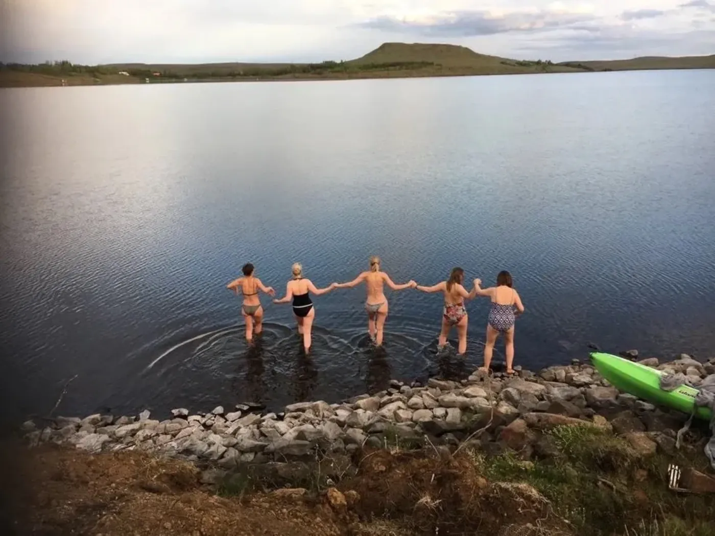 Five women walking hand in hand into a cold lake