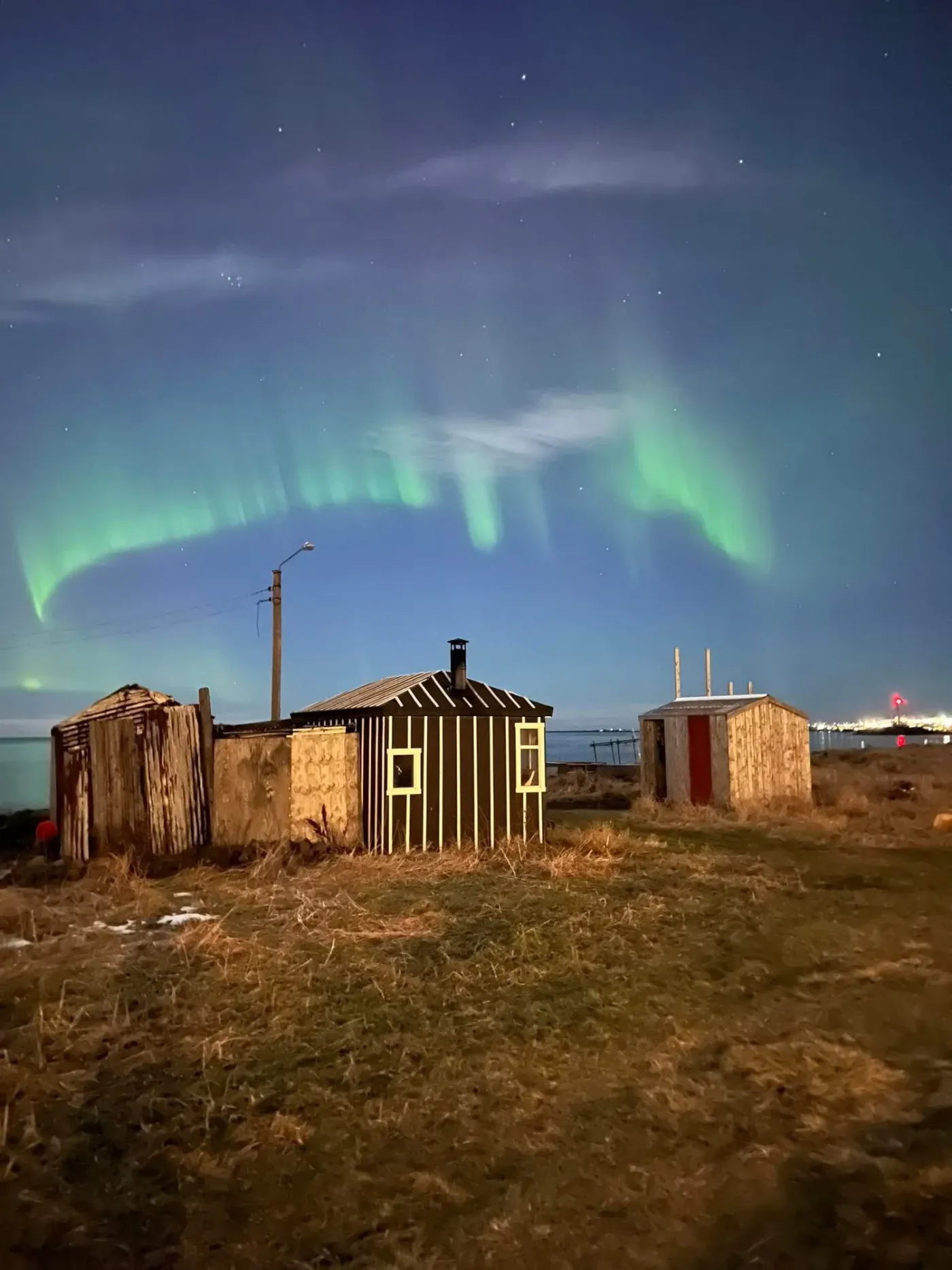 The seaside sauna huts at Sækot under a green aurora