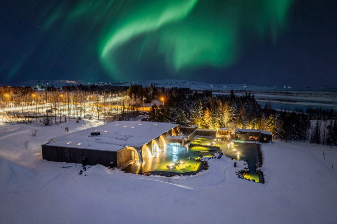 A geothermal lagoon lit at night under the northern lights
